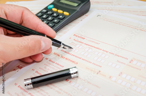 close-up of a woman's hand with a pen fills out Australian tax forms. Financial document. Tax time. Close-up.