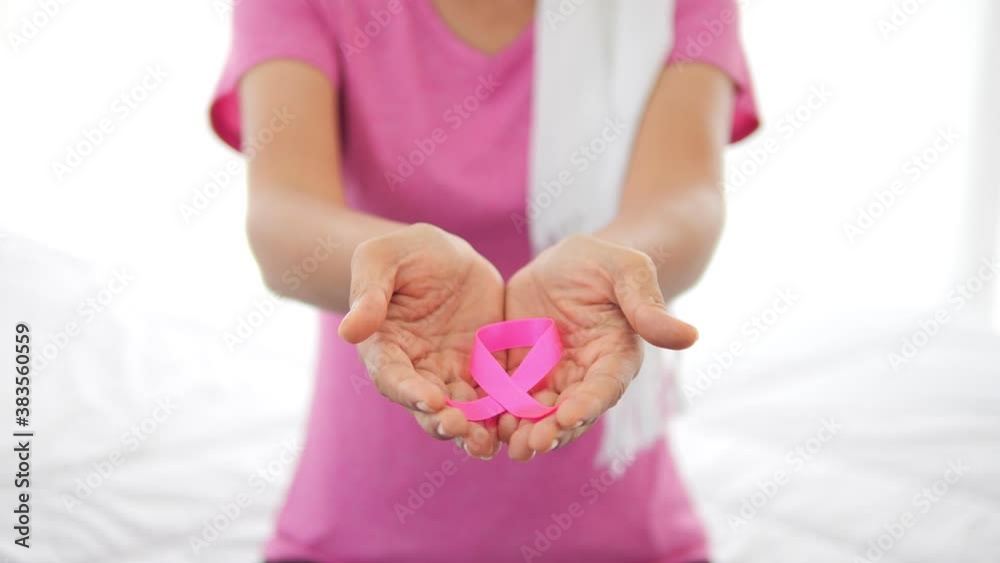 Close up of Hand holding pink ribbon to camera. World breast cancer day concept. Breast cancer symbol. Close up of Hand holding pink ribbon to camera. World breast cancer day concept. Breast cancer symbol.