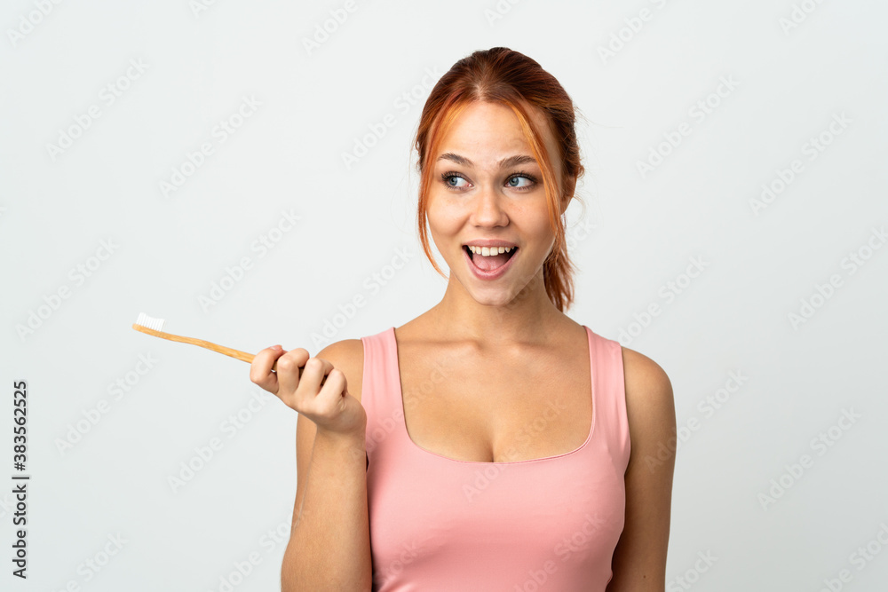 Teenager Russian girl isolated on white background with a toothbrush and surprised expression Teenager Russian girl isolated on white background with a toothbrush and surprised expression
