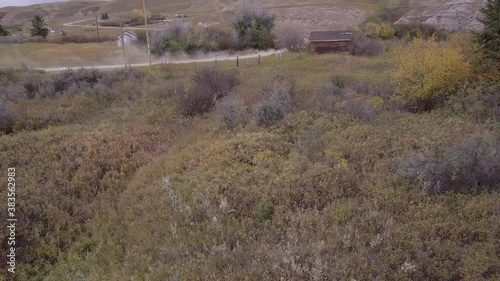 Panning aerial as white car drives romote dirt road in rural badlands photo