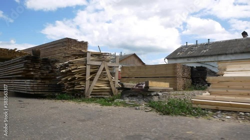 Motion past huge piles of long wooden boards stacked in contemporary woodworking factory yard under blue cloudy sky photo