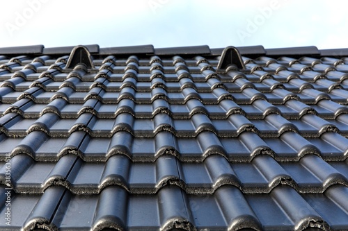 Construction of a family house in the village. Construction site roofing black tiles. black tile roof on residential building construction house.