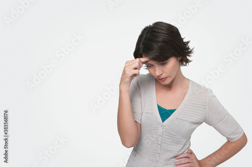 Obraz na plátně Tensed woman standing with head in hand on white background