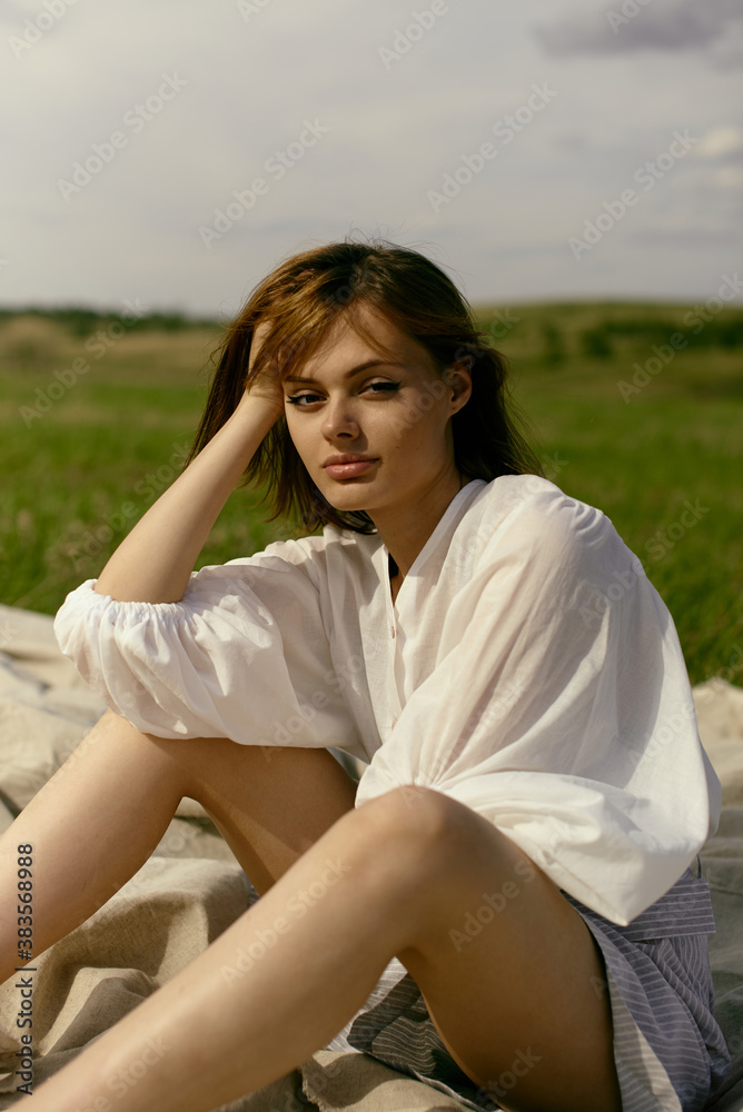 Nice picnic on the grass. Young beautiful woman in the middle of green field. Summer landscape, good weather. Windy day with sun and clouds. Cotton white suit eco style. Nice picnic on the grass. Young beautiful woman in the middle of green field. Summer landscape, good weather. Windy day with sun and clouds. Cotton white suit eco style.