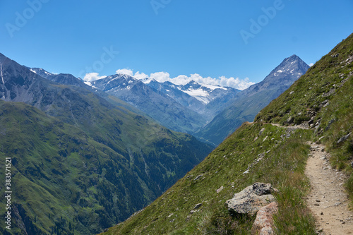 Bergweg am Rand eines grünen Berges beim Wandern in den Bergen Alpen Wanderweg