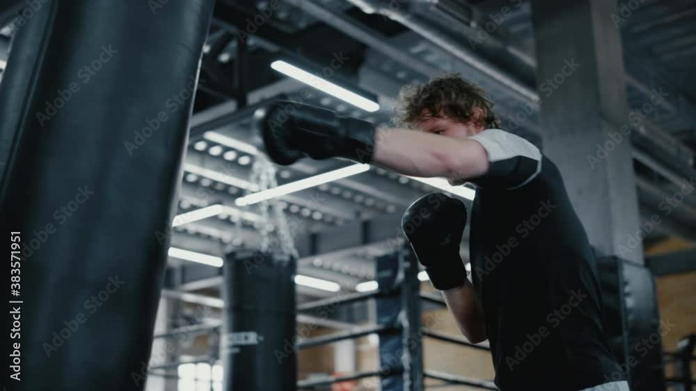 Agitated fighter working on blows in fitness center. Sportsman training kicks Agitated fighter working on blows in fitness center. Sportsman training kicks