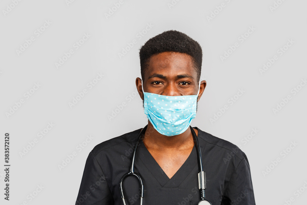 Confident male doctor. Cheerful african doctor in medical mask standing against gray background Confident male doctor. Cheerful african doctor in medical mask standing against gray background