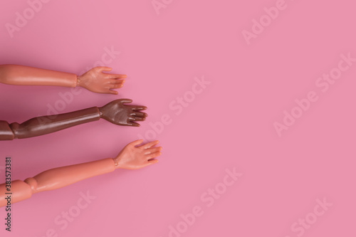 Three doll hands on pink background. Different skin tones and races. Stop racism, diversity and unity, equality and feminism creative concept. Place for text, top view, layout