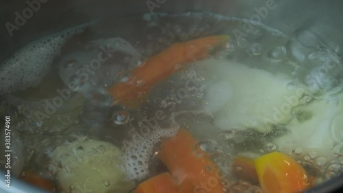 Chicken soup with vegetables boiling in a pot close-up. Home diet food concept