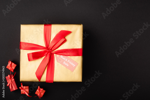 Top view of gift with price tag and black friday sale on black background