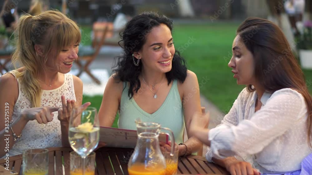 Three beautiful women having fun choosing meal, looking at the menu, laughing and gesturing Three beautiful women having fun choosing meal, looking at the menu, laughing and gesturing