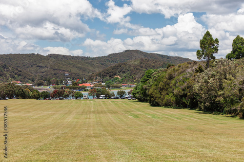 Rolling landscape with meadow, trees, sea and car park in Waitangi, Bay of Islands, New Zealand