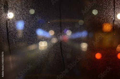 raindrops flow down the glass against the background of the night city