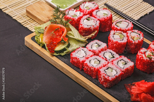 Close-up japanese sushi roll set with red flying fish caviar. Pickled ginger, spicy wasabi paste and soy sauce. Copy space
