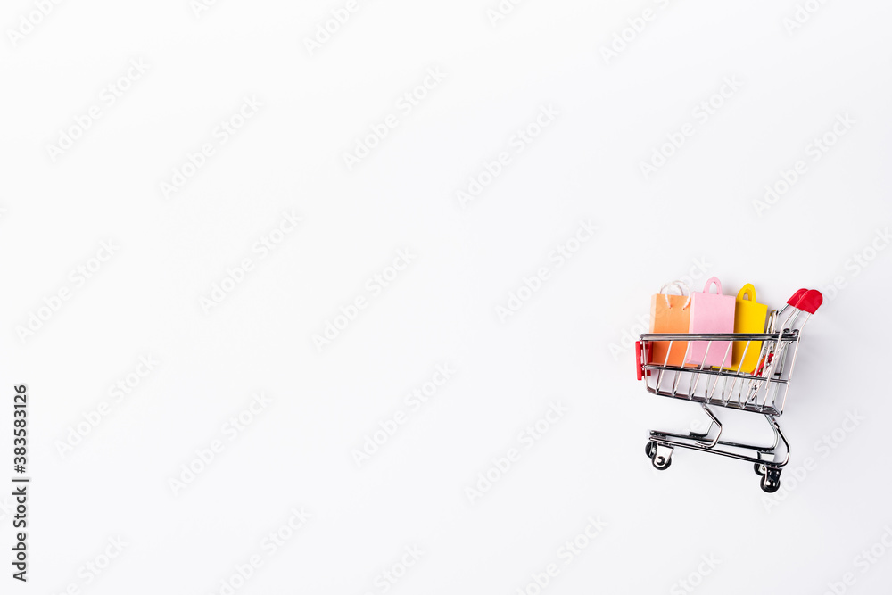 Top view of colorful toy shopping bags in cart on white background