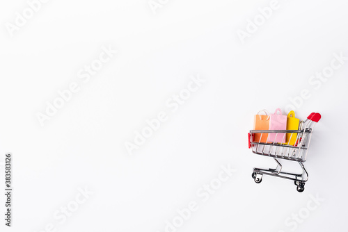 Top view of colorful toy shopping bags in cart on white background