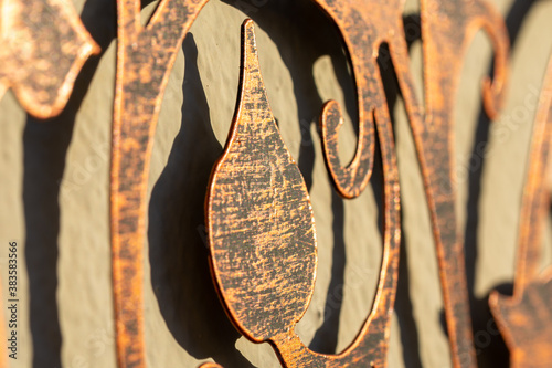 Photography Detail of a coppery metal ornament and its shadow on a wall