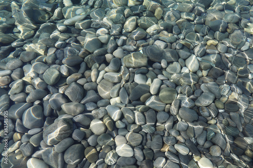 Canvas Print Top view of stones under water on shallow water on a sunny day in flat lay