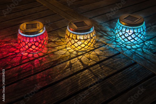 Garden Lamps. Isolated. Copy Space. Decorative small colorful solar lamps on a wooden garden table at night. Stock Image.