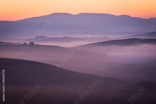 foggy valley in purple and orange colors, autumn early morning, italy, tuscany