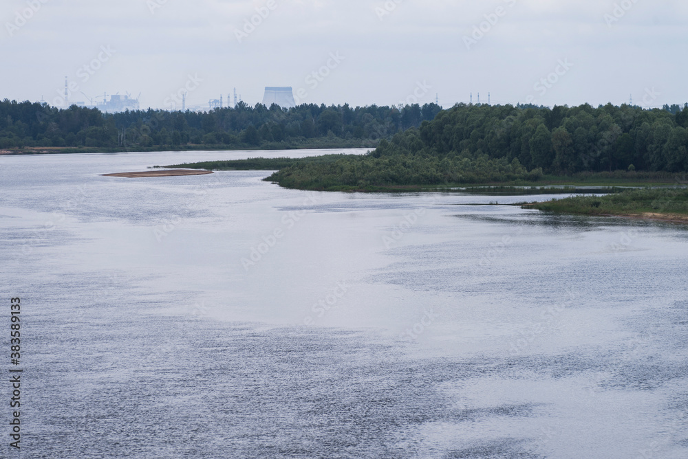 River Pripyat in Chernobyl exclusion zone with nuclear power plant on horizon