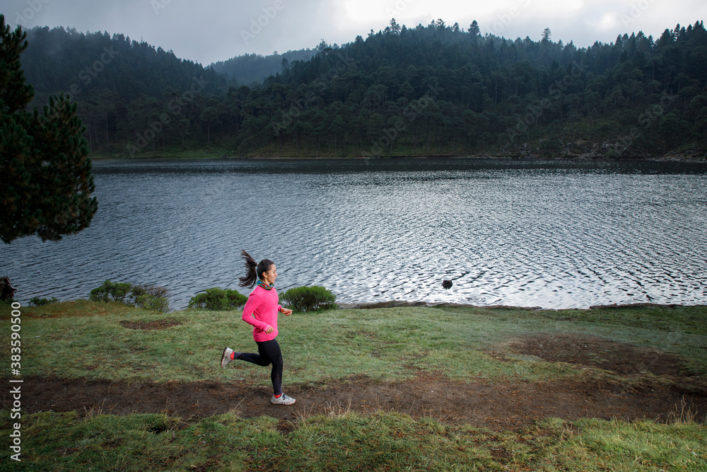 Atleta corriendo al aire libre cerca de un lago con montañas al fondo Atleta corriendo al aire libre cerca de un lago con montañas al fondo