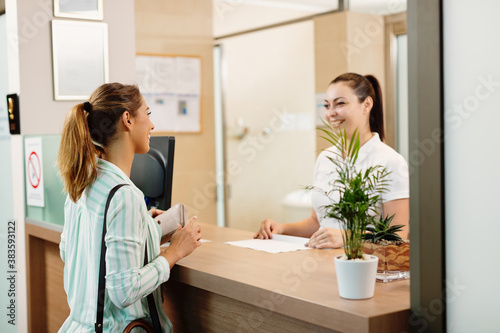 Happy woman talking to a receptionist while arriving at the spa. photo