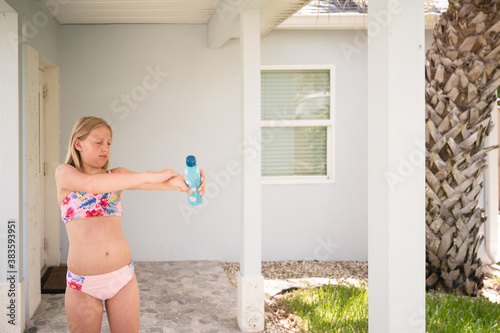 Tween Girl Wearing Bathing Suit Applying Sunscreen in Florida photo