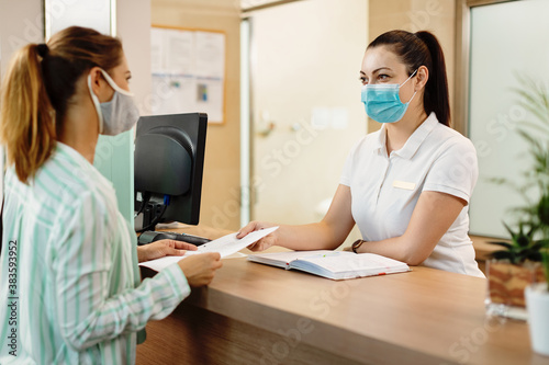 Health spa receptionist and her customer wearing face masks due to coronavirus pandemic. photo