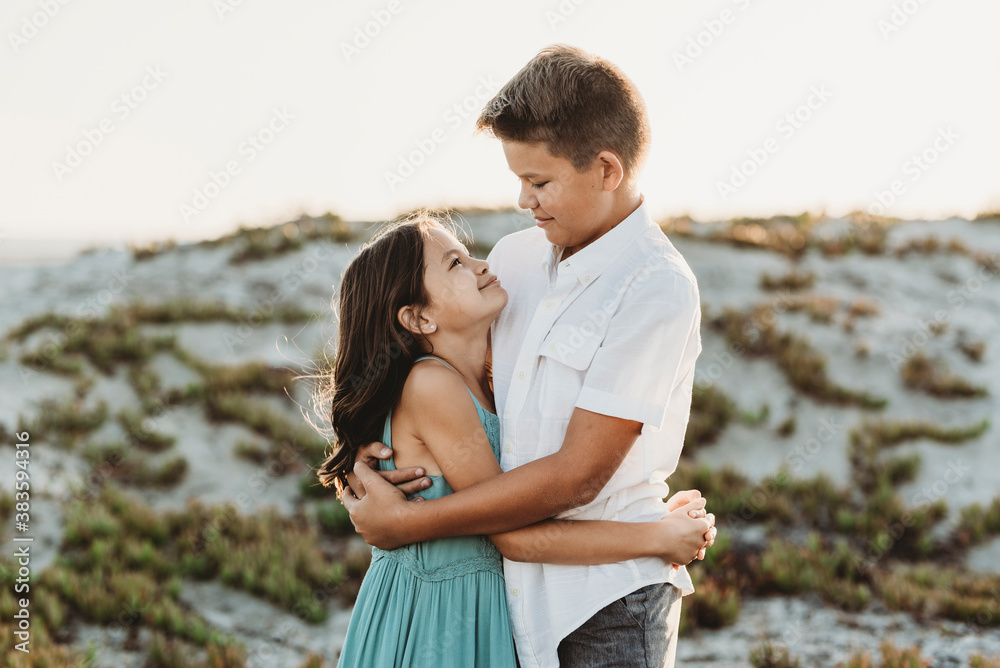 Preteen brother hugging younger sister at the beach Preteen brother hugging younger sister at the beach