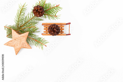 Christmas background frame of fir twigs, wooden zero waste home decotarion: sleigh, stars and chistmas tree on white background, top view. Reusable sustainable recycled decor. Eco friendly new year photo