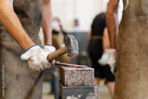 Fotografie, Obraz Crop blacksmiths hitting hot metal detail with hammer while forging