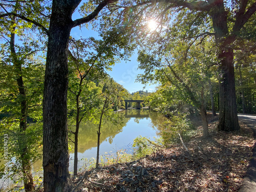 Sun through the trees of autumn over a country pond.