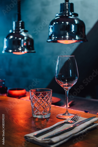 Glasses on the table in red light of infrared heat lamps in restaurant photo