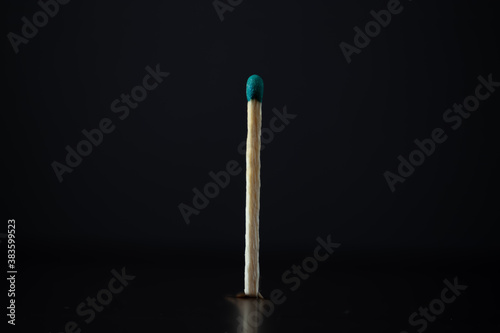 Single extinguished wooden match with black background. Frontal plane