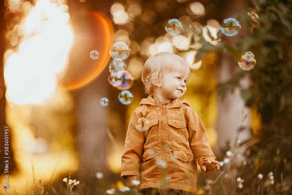 Cute baby boy walking in the beige jacket at sunset