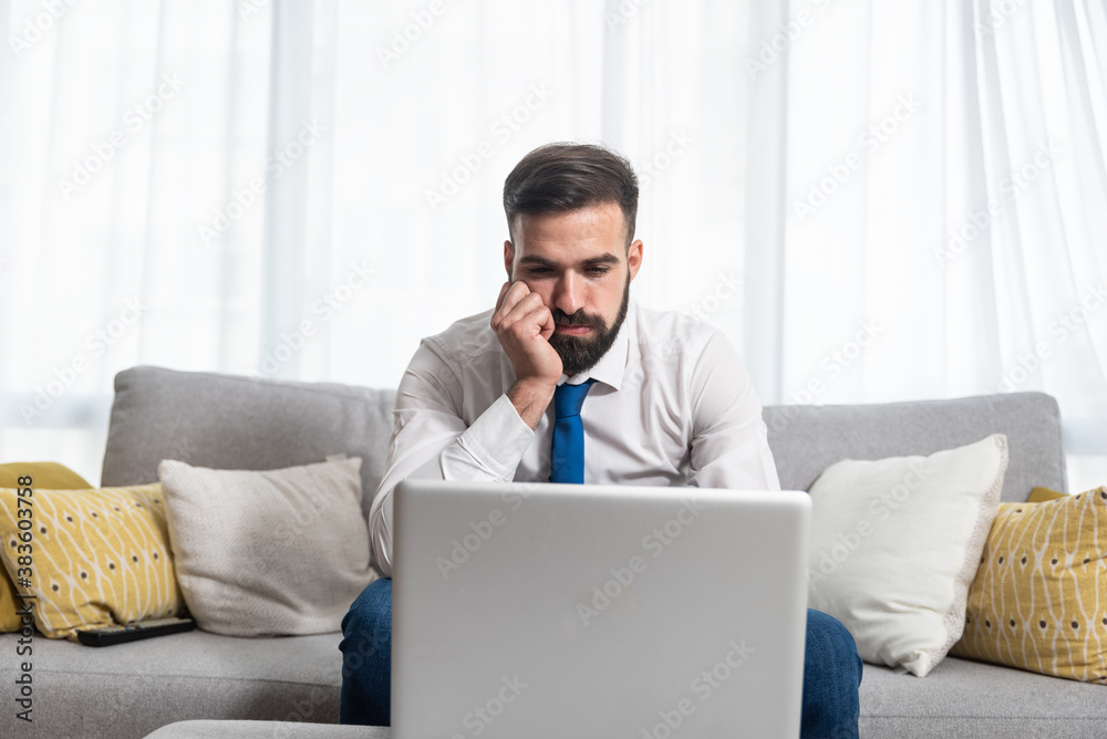 Young stressed freelancer business man in shirt and necktie looking at his laptop computer screen reading negative charts and statistic after crisis and crash of the market Young stressed freelancer business man in shirt and necktie looking at his laptop computer screen reading negative charts and statistic after crisis and crash of the market