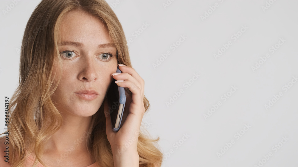 Young shocked woman talking on smartphone isolated on white back Young shocked woman talking on smartphone isolated on white back
