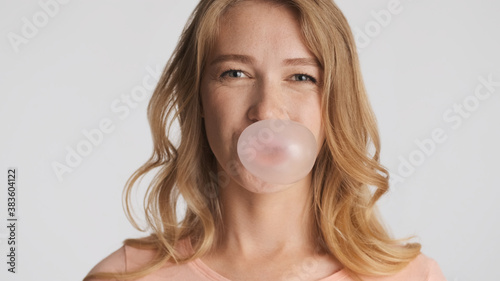 Pretty funny girl happily blowing bubblegum isolated on white ba