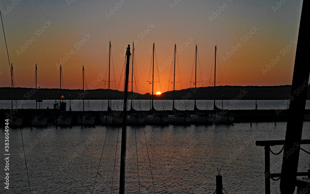 The silhouette of yacht masts against the setting sun.
