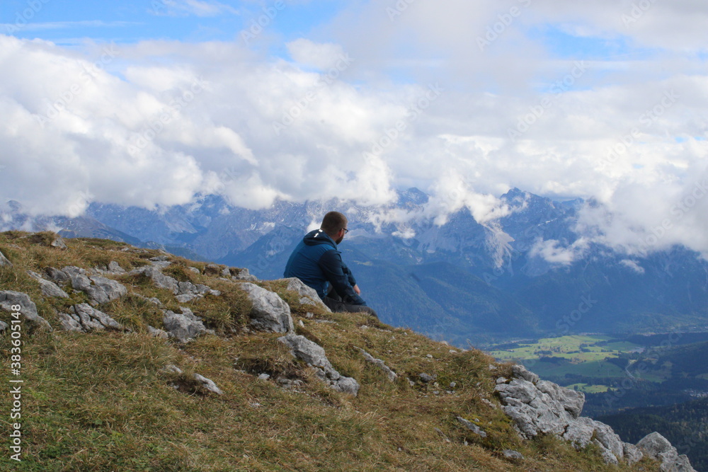 A lonely hiker enjoying the silence and great view across the alps on a beautiful day in autumn
