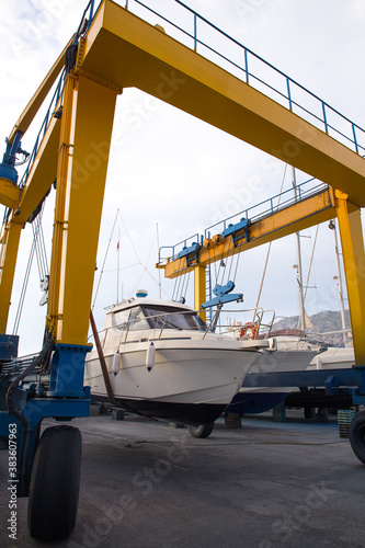 Boat wheel crane elevating motorboat to yearly paint photo