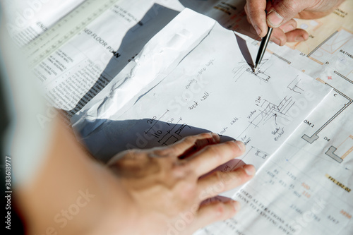 Worker's hands on building plans at construction site photo