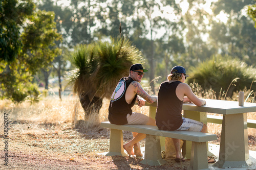 Back view of two guys sitting at a picnic table in a rural setting photo