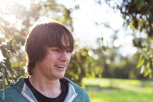 Young man with hair in his eyes backlit with sun flare photo