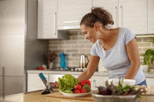 Beautiful smily handsome woman is preparing tasty fresh healthy salad at her kitchen at home