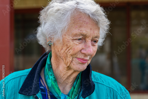 head and shoulders of old lady with grey hair and wrinkled skin looking away photo