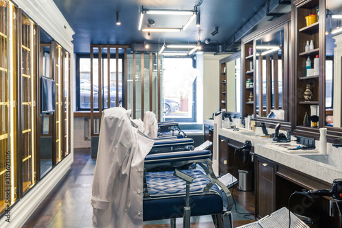 luxury barber shop interior, blue expensive furniture, wood trim, fashionable black ceiling, white robes on the backs of armchairs © 4595886