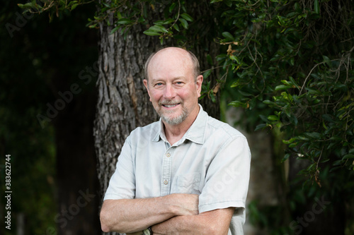 Elderly man smiling with arms folded looking at camera photo