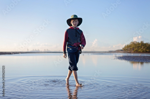 Boy walks on the beach at lowtide in winter barefoot photo